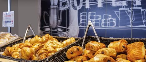 Una exhibición de pasteles variados en cestas de mimbre, con un fondo que muestra un cartel de pizarra que dice 'BUFFET'.
