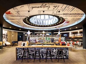 Un área de bar moderna con un diseño de techo circular, una barra, taburetes y un menú de pizzas.