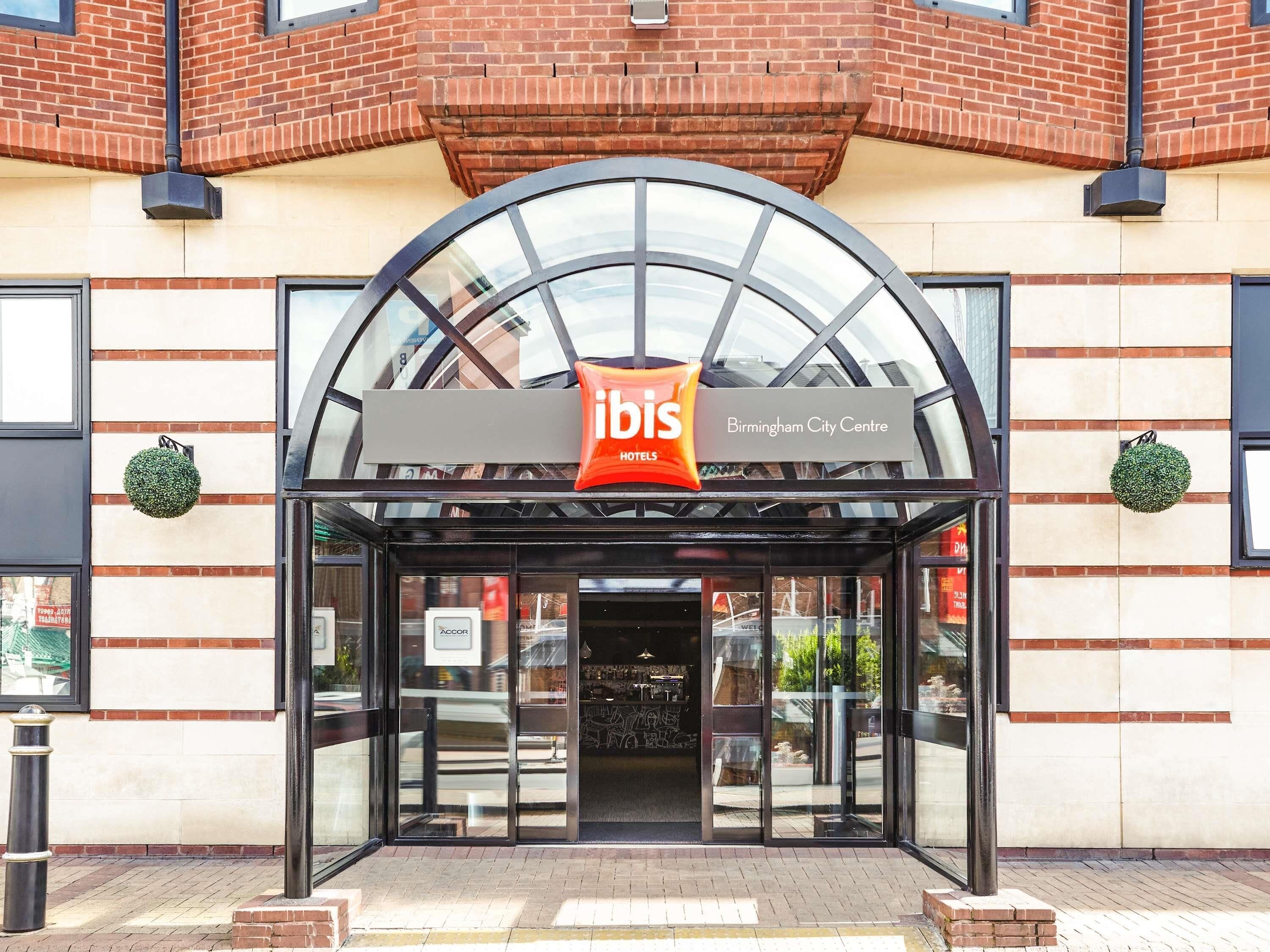 La entrada del hotel ibis Birmingham City Centre, con fachada de vidrio y un cartel sobre la entrada.