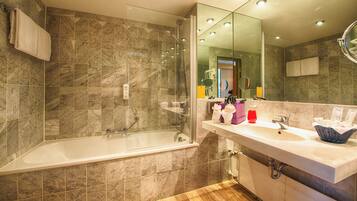 Ein modernes Badezimmer mit einer gläsernen Duschkabine, einem weißen Waschbecken mit Marmorplatte und einem Holzboden.