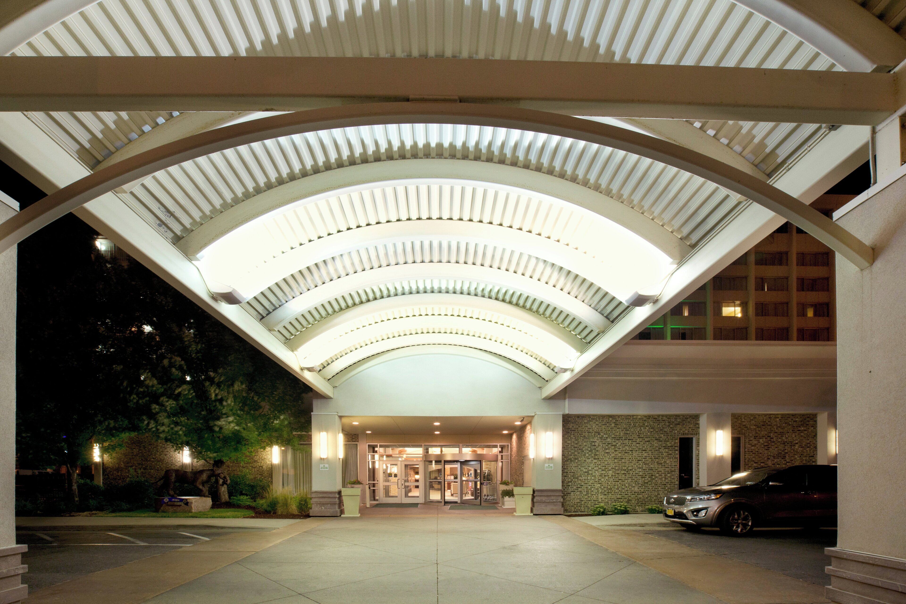 A hotel entrance with a covered walkway, a brick building, and a parked car.