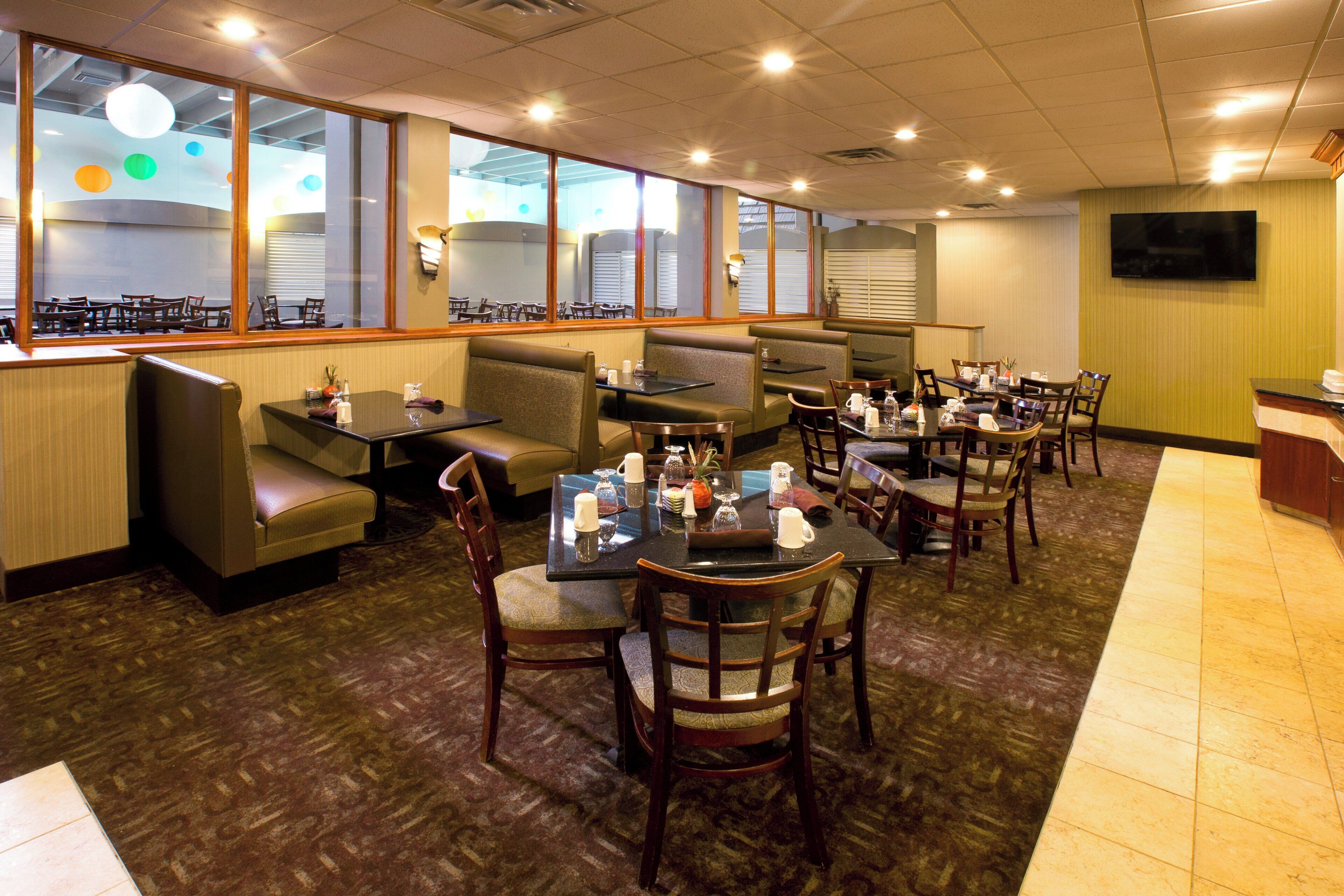 A restaurant with booths and tables, a TV on the wall, and a patterned carpet.