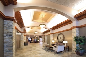 A hotel lobby with a high ceiling, stone walls, and a large clock. - Holiday Inn Sioux Falls-City Centre by IHG (Sioux Falls)