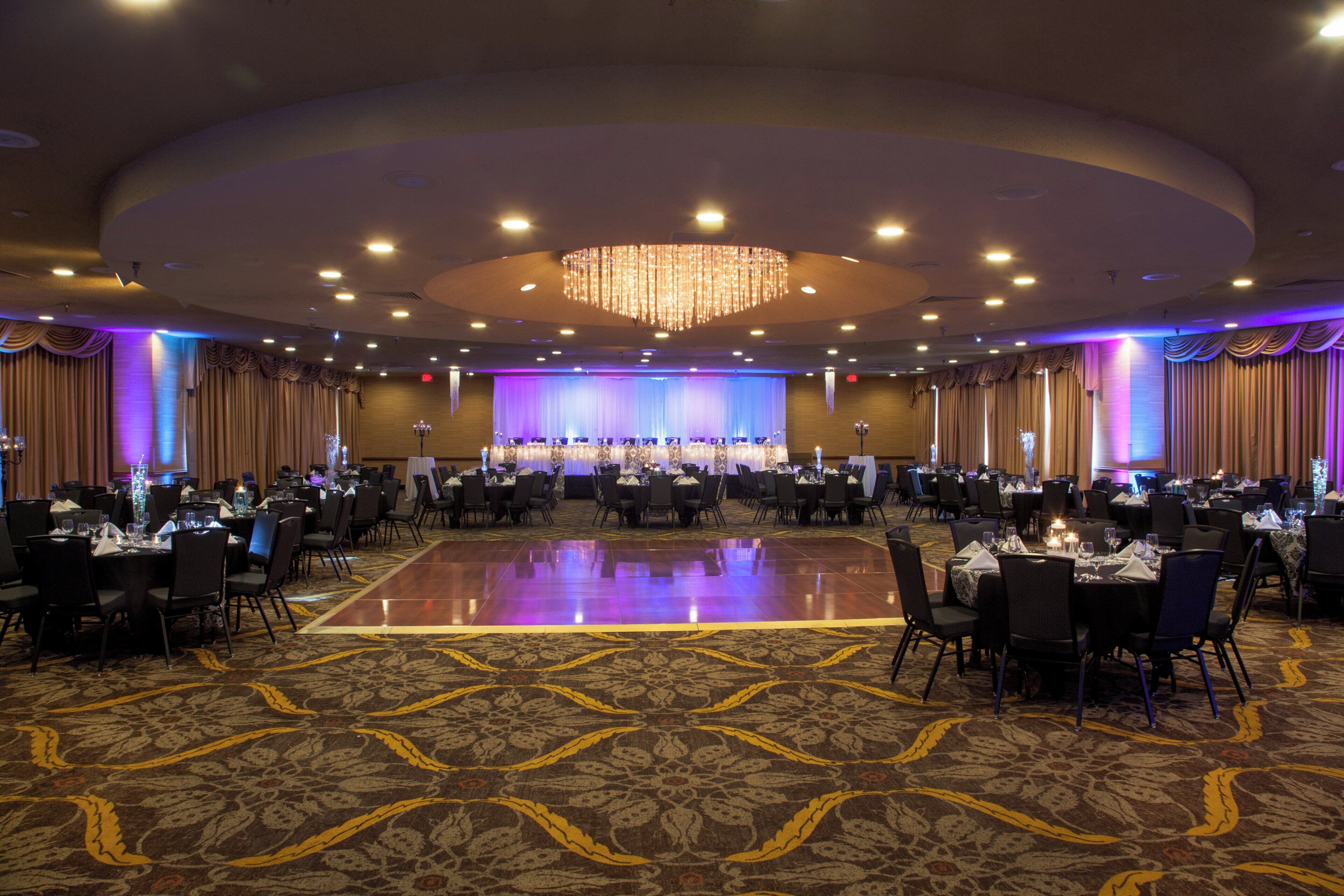 A banquet hall with a central stage, multiple round tables, and a patterned carpet.