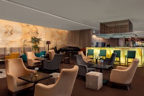 A modern lounge area with plush seating, a piano, and a bar with a unique glass top.