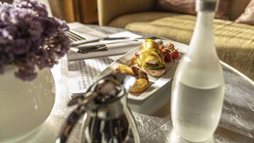 A dining table with a meal, a salt shaker, a water bottle, and a vase of flowers.