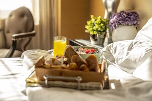 A breakfast tray with toast, fruit, and orange juice on a bed in a hotel room.
