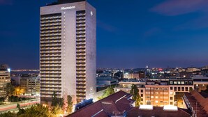 Un hotel alto con el nombre 'Sheraton' en su fachada, que cuenta con varios pisos y un diseño arquitectónico moderno.