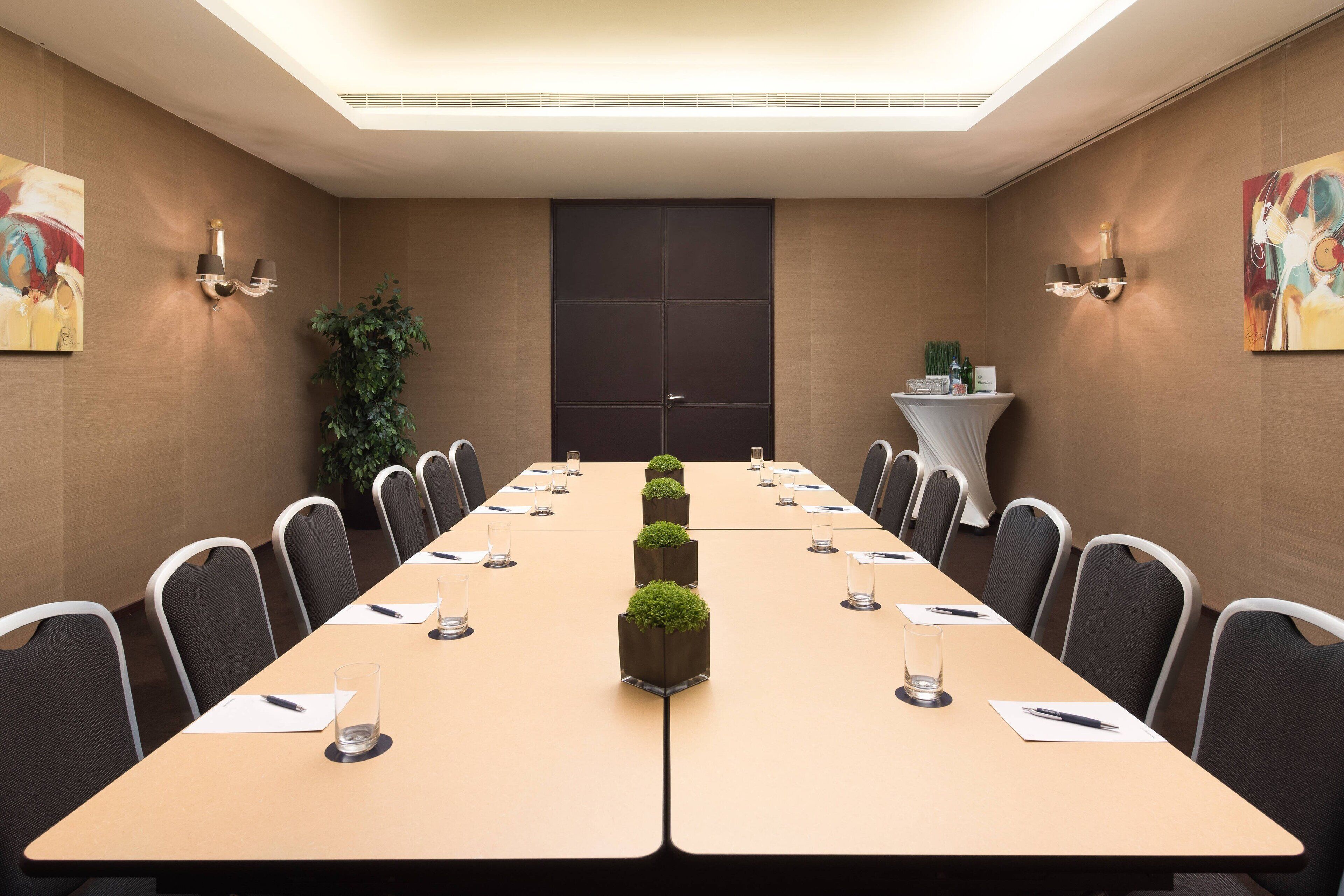 A conference room with a long table, chairs, and a small plant centerpiece.