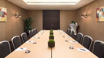 A conference room with a long table, chairs, and a small plant centerpiece.