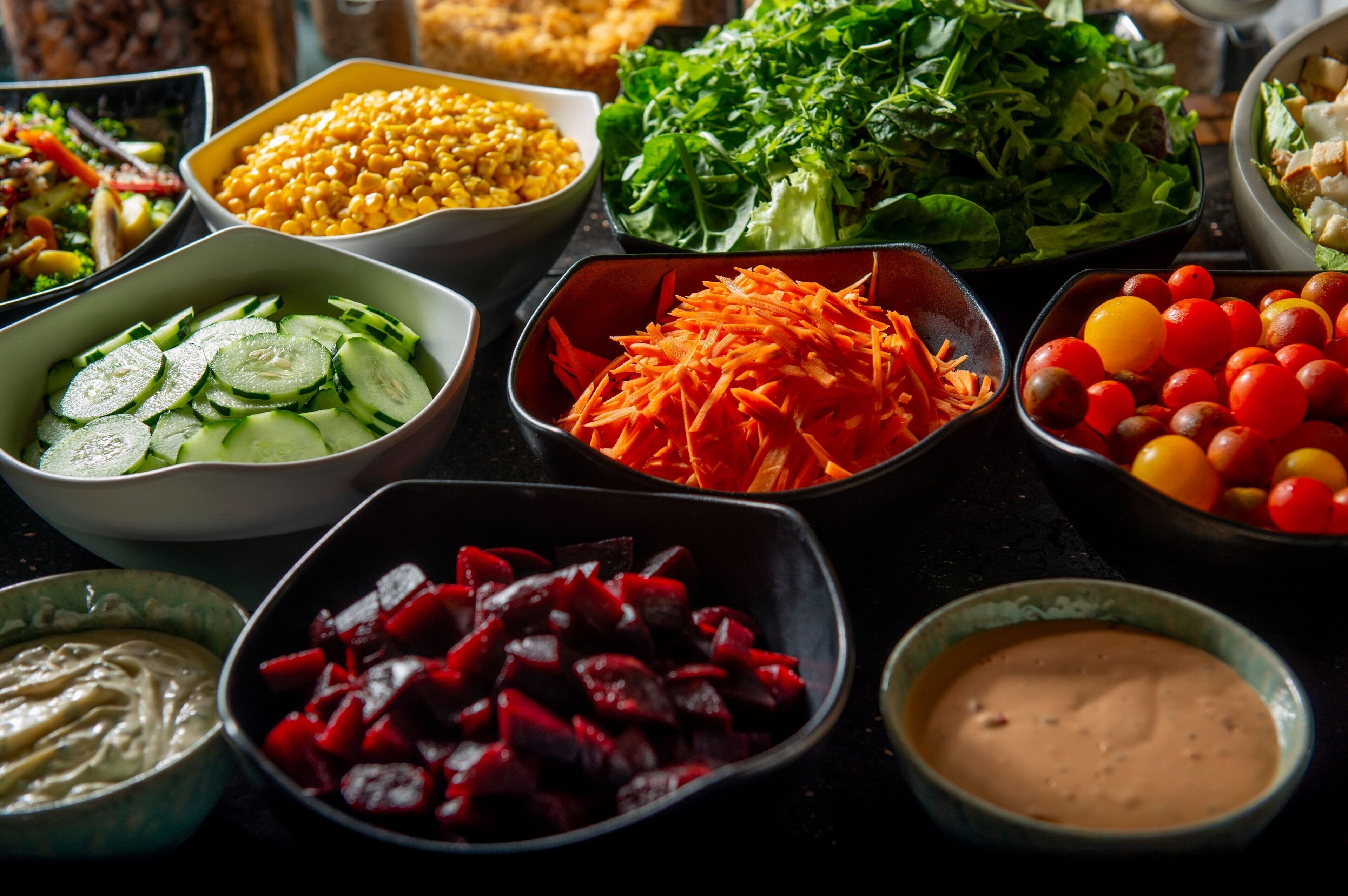 A variety of food items including vegetables, salads, and dips arranged on a table.