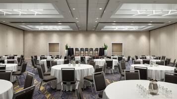 Un salón de conferencias con mesas redondas, sillas y una alfombra estampada.
