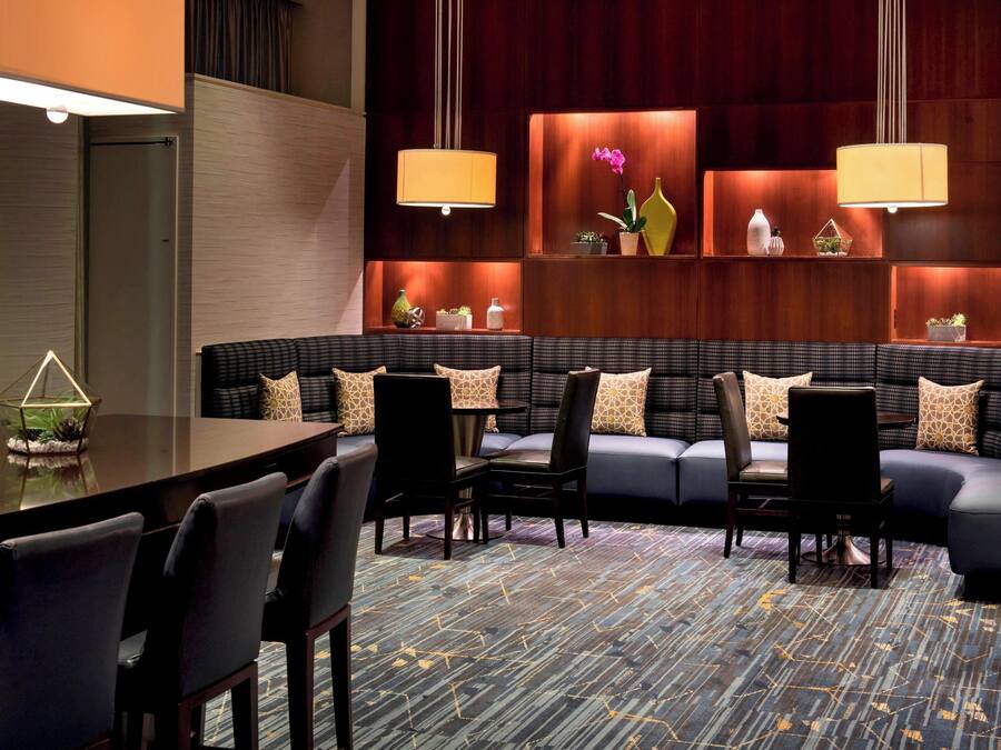 A modern hotel lobby with a seating area, a long table, and decorative plants.
