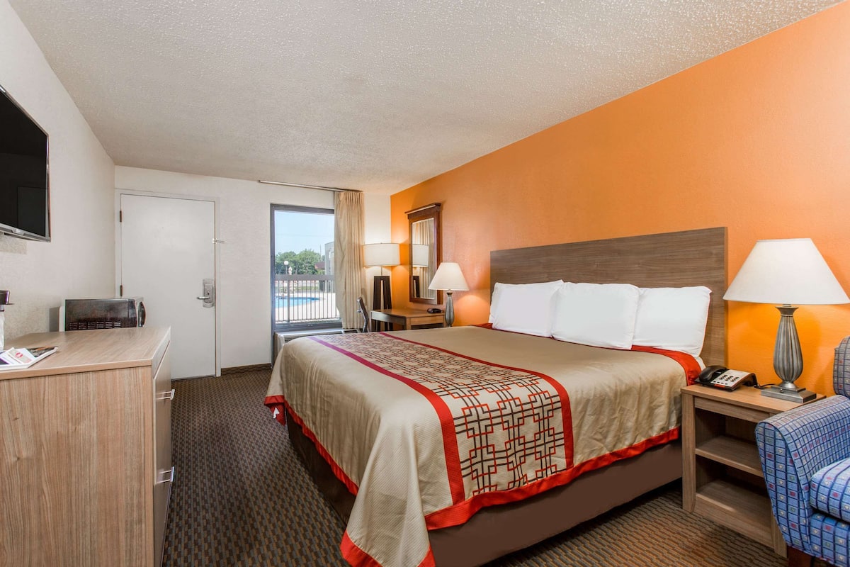 A hotel room with a large bed, a desk, a chair, and a television.