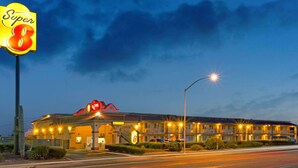 Un motel con un gran letrero de 'Super 8', un toldo rojo y un estacionamiento.