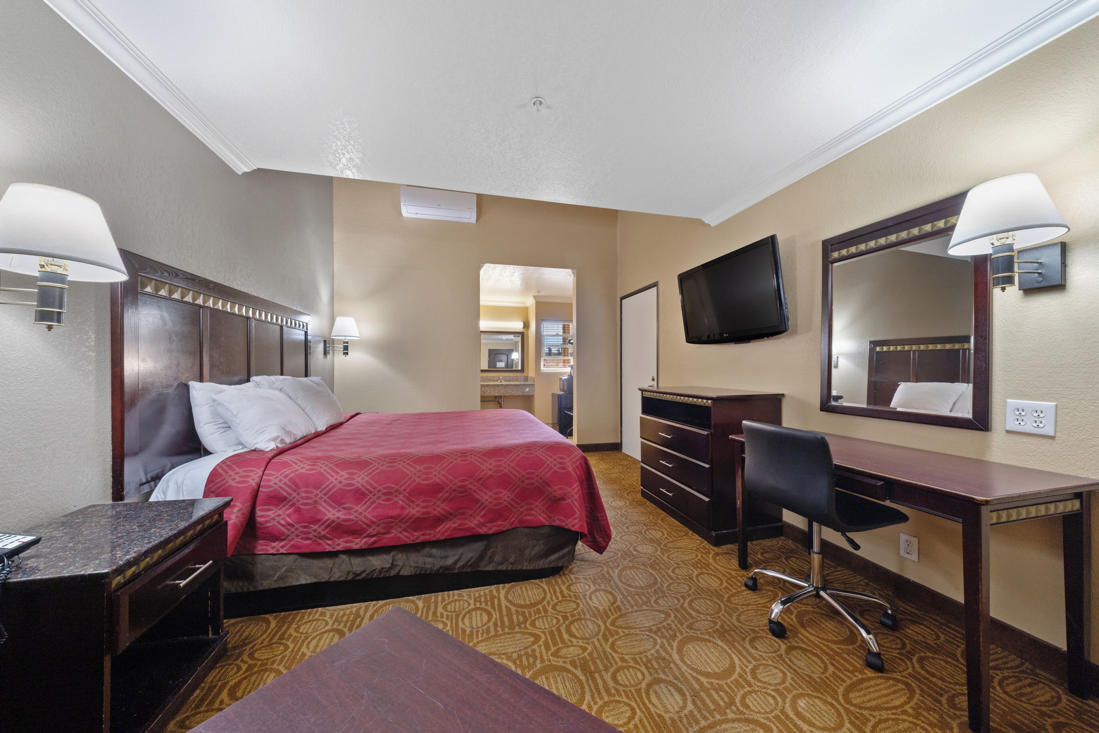 Une chambre d’hôtel équipée d’un lit, d’un bureau, d’une chaise, d’une télévision et d’un miroir.