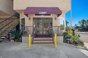 A building entrance with a 'Lobby' sign, a staircase, and a 'Welcome' sign.