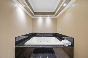 A modern bathroom with a large bathtub, marble countertops, and a ceiling with recessed lighting.