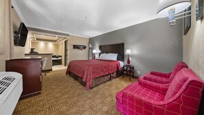 Une chambre d’hôtel équipée d’un lit, d’un bureau, d’une chaise, d’un canapé et d’un téléviseur fixé au mur.