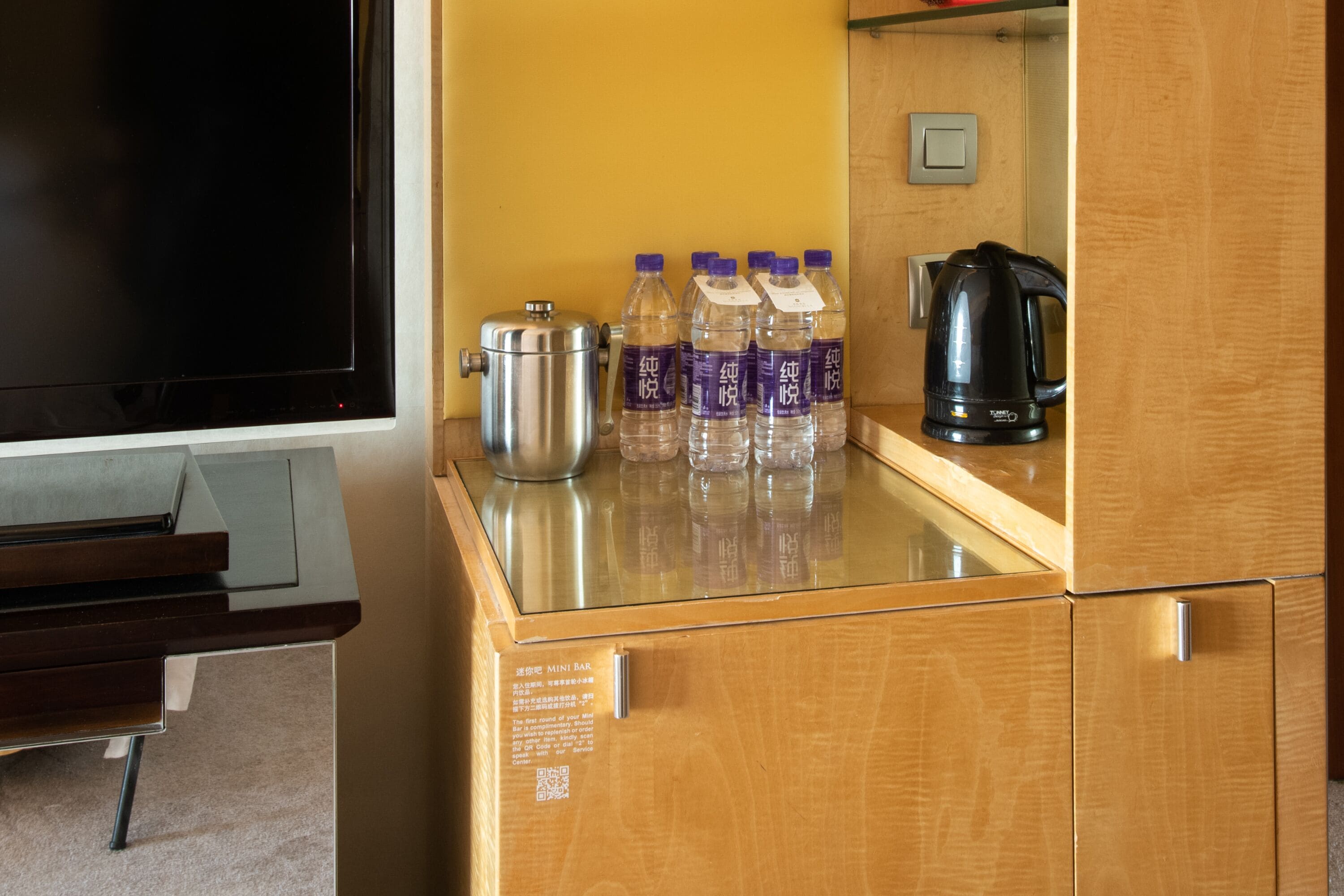 A minibar with a TV, a kettle, and bottled water.