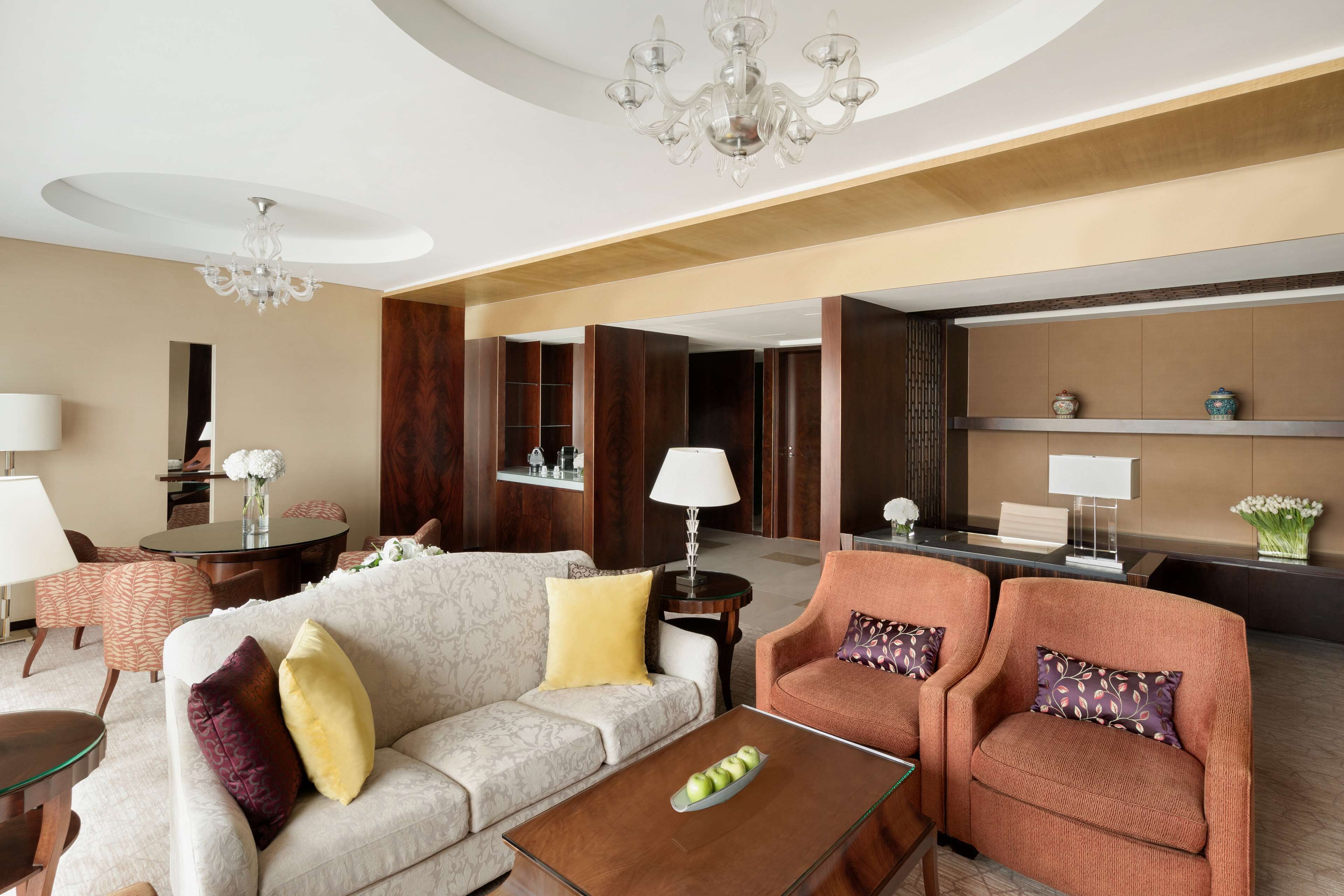 A modern hotel lobby with a sofa, armchairs, a coffee table, and a reception desk.