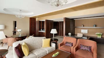 A modern hotel lobby with a sofa, armchairs, a coffee table, and a reception desk.