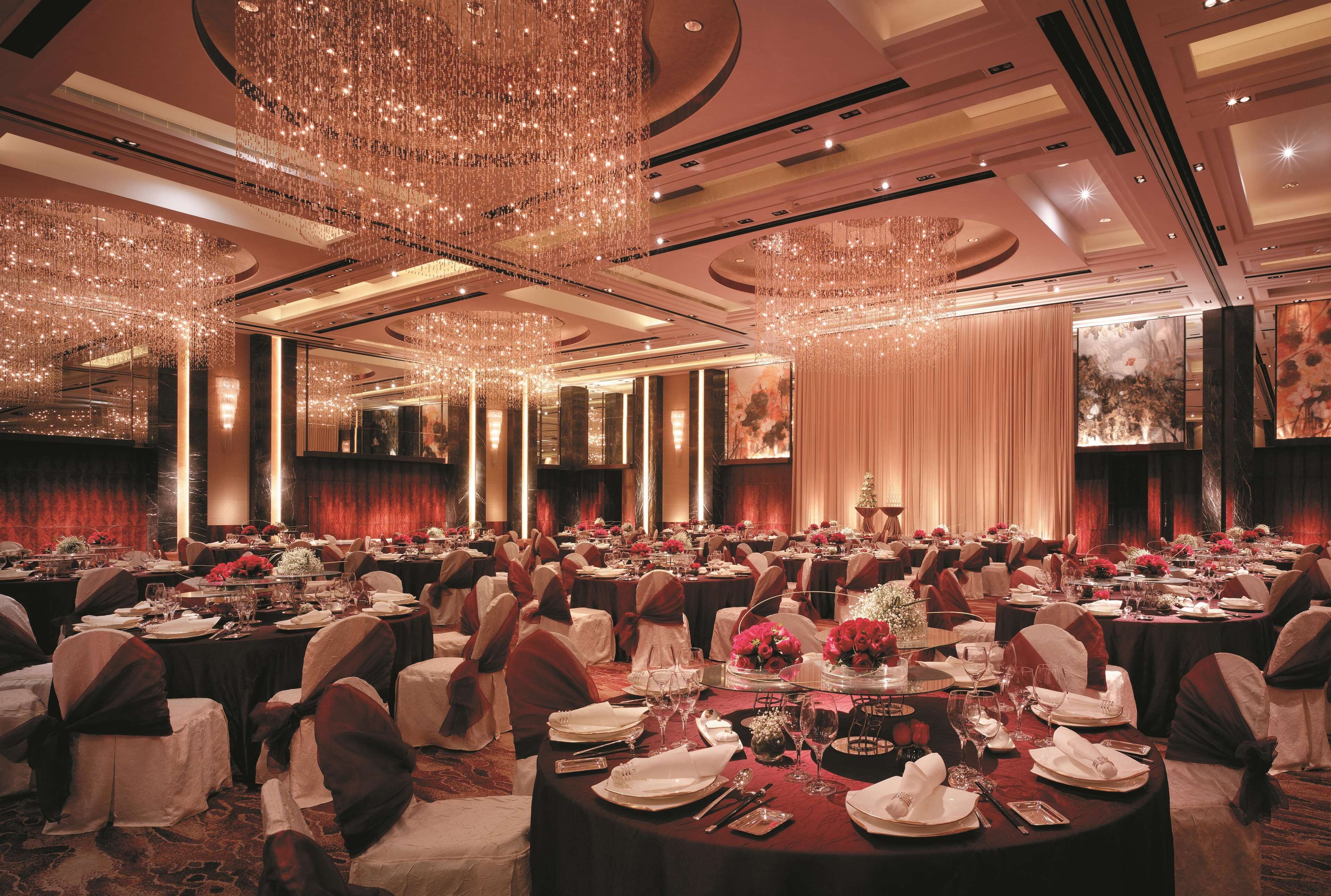 Un salón de banquetes con mesas redondas, sillas y candelabros.