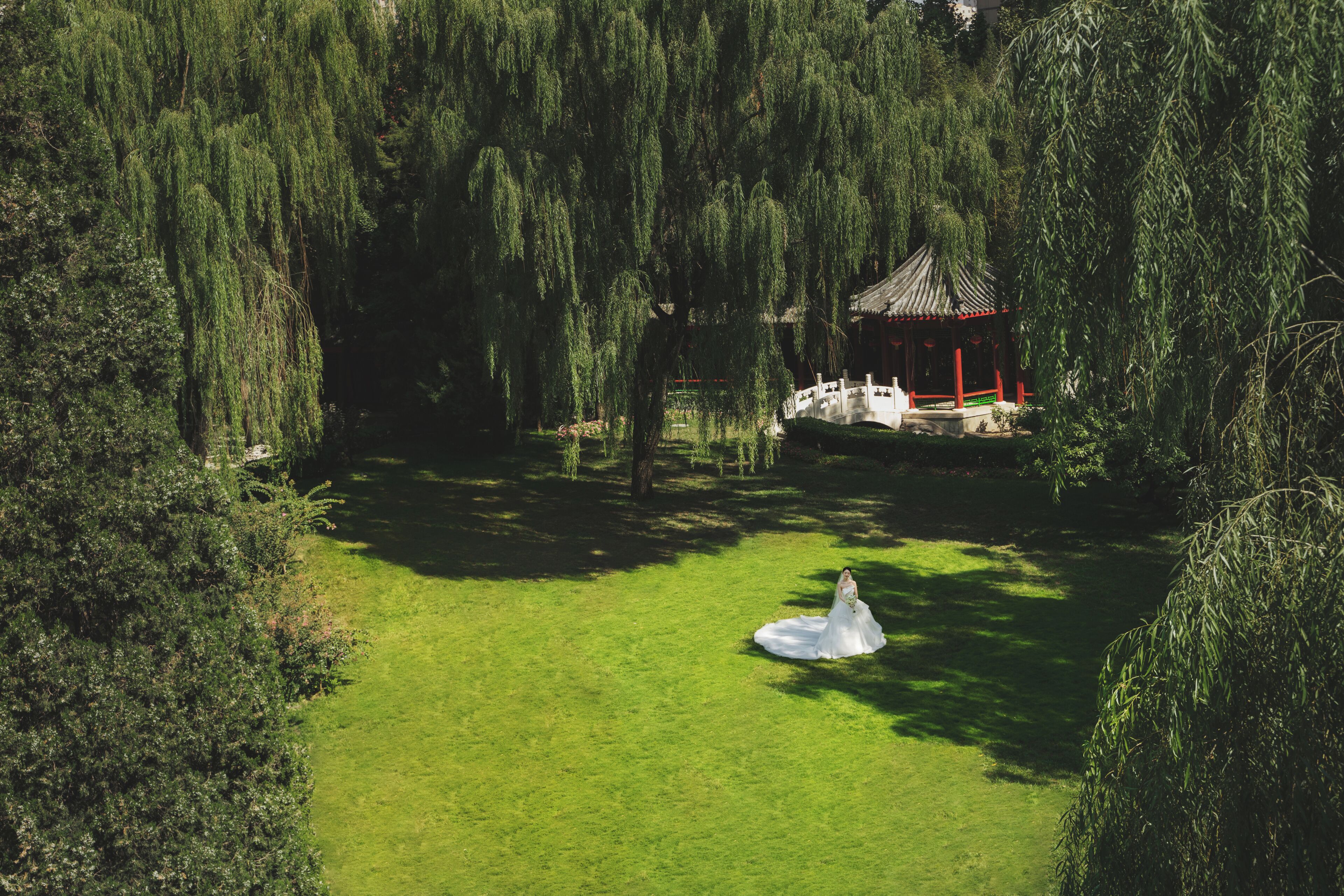 Un parc paisible avec un pavillon, une végétation luxuriante et une statue blanche.