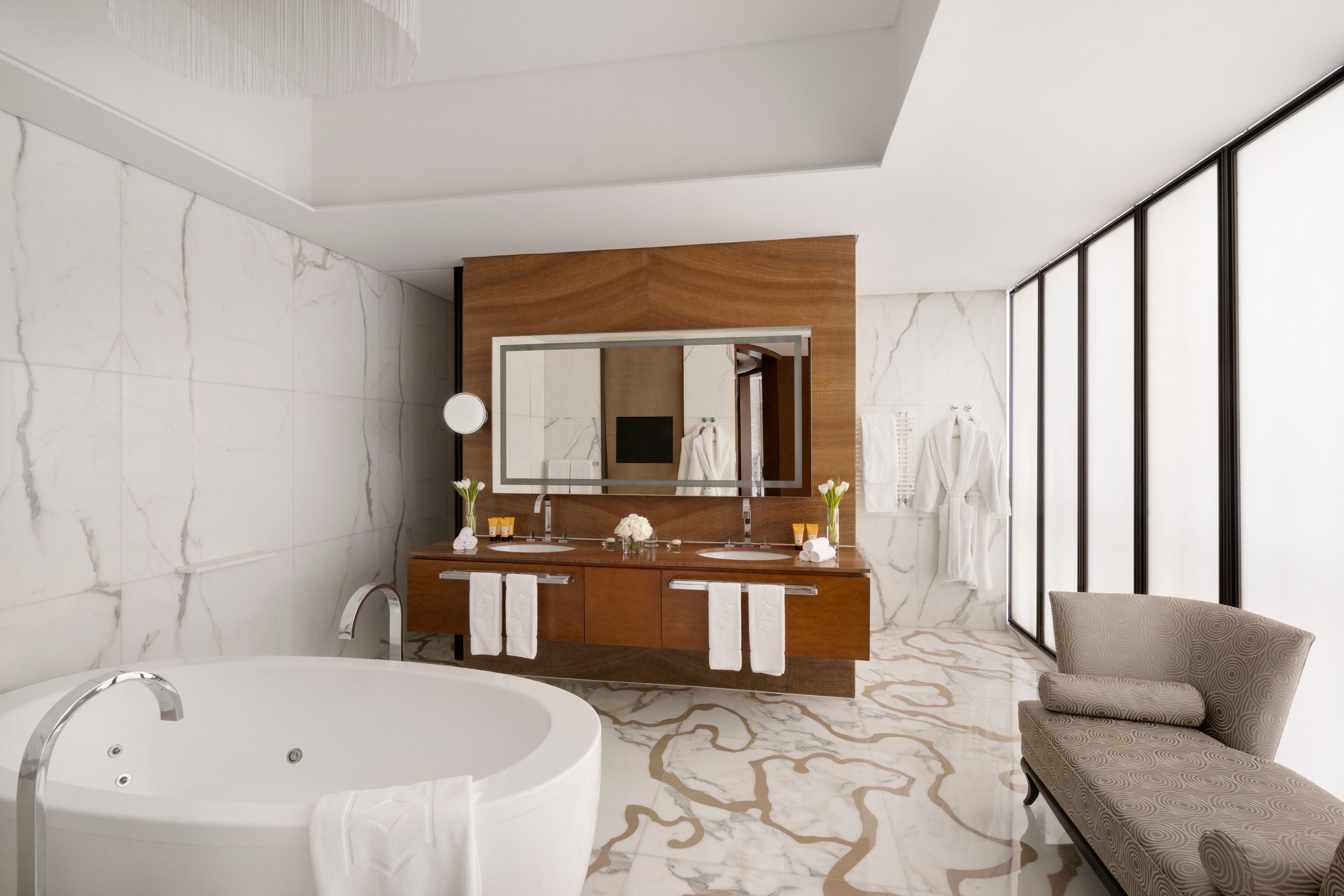 A modern bathroom with a freestanding bathtub, dual sinks, and a large mirror.
