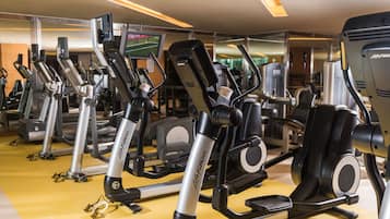 Un gimnasio con diversas máquinas de ejercicio, incluyendo cintas de correr y elípticas, dispuestas en filas.