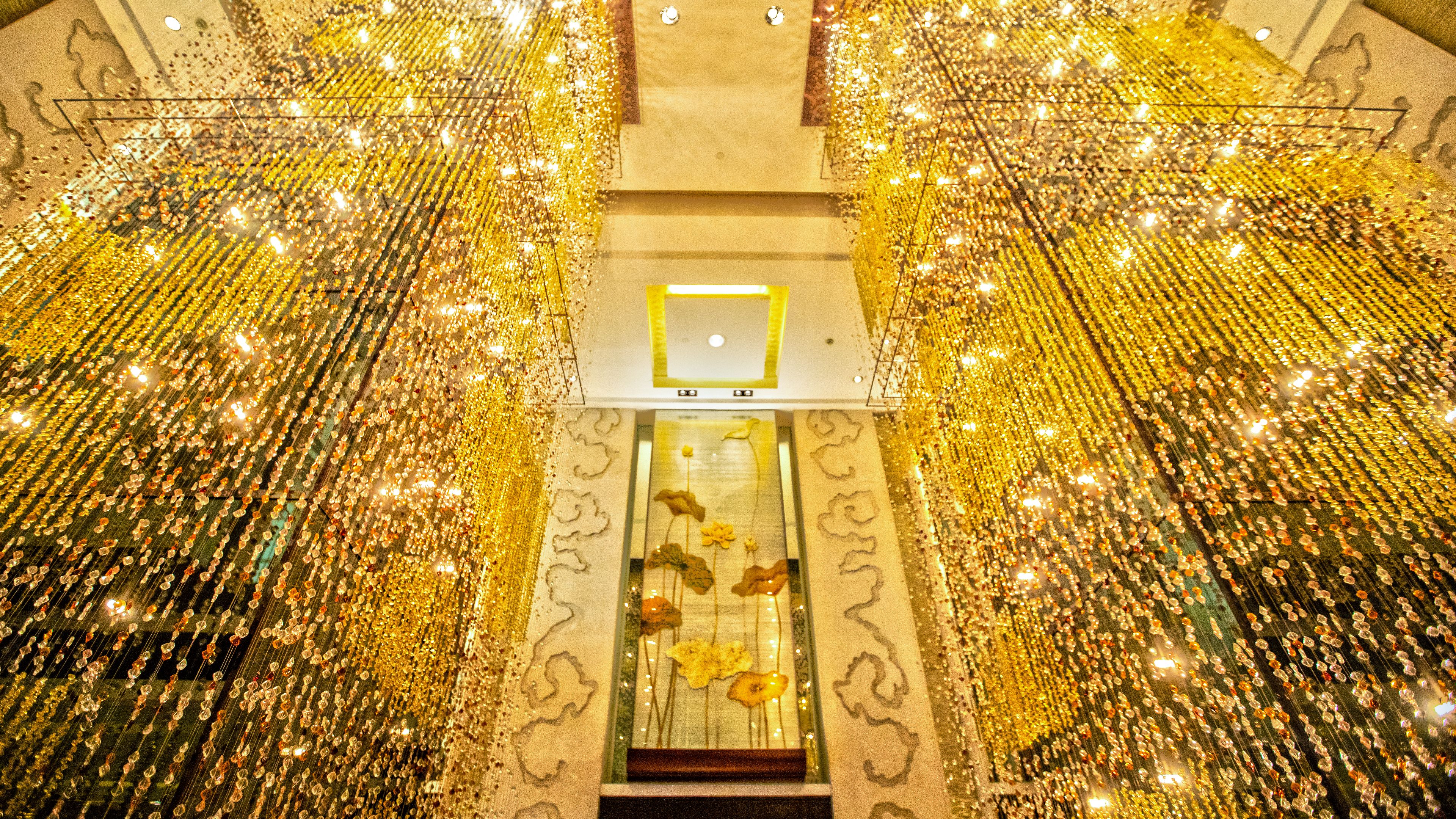 A ceiling with golden decorations and a central glass panel with floral designs.