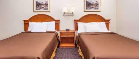 Una habitación de hotel con dos camas individuales, una mesita de noche con lámparas y dos cuadros en la pared.