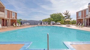 A rectangular swimming pool with a metal safety rail in the center, surrounded by lounge chairs and a paved deck. - Travelodge by Wyndham Jackson (Jackson)
