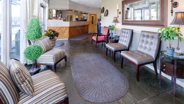 A lobby with striped sofas, a reception desk, and a large mirror. - Travelodge by Wyndham Jackson (Jackson)