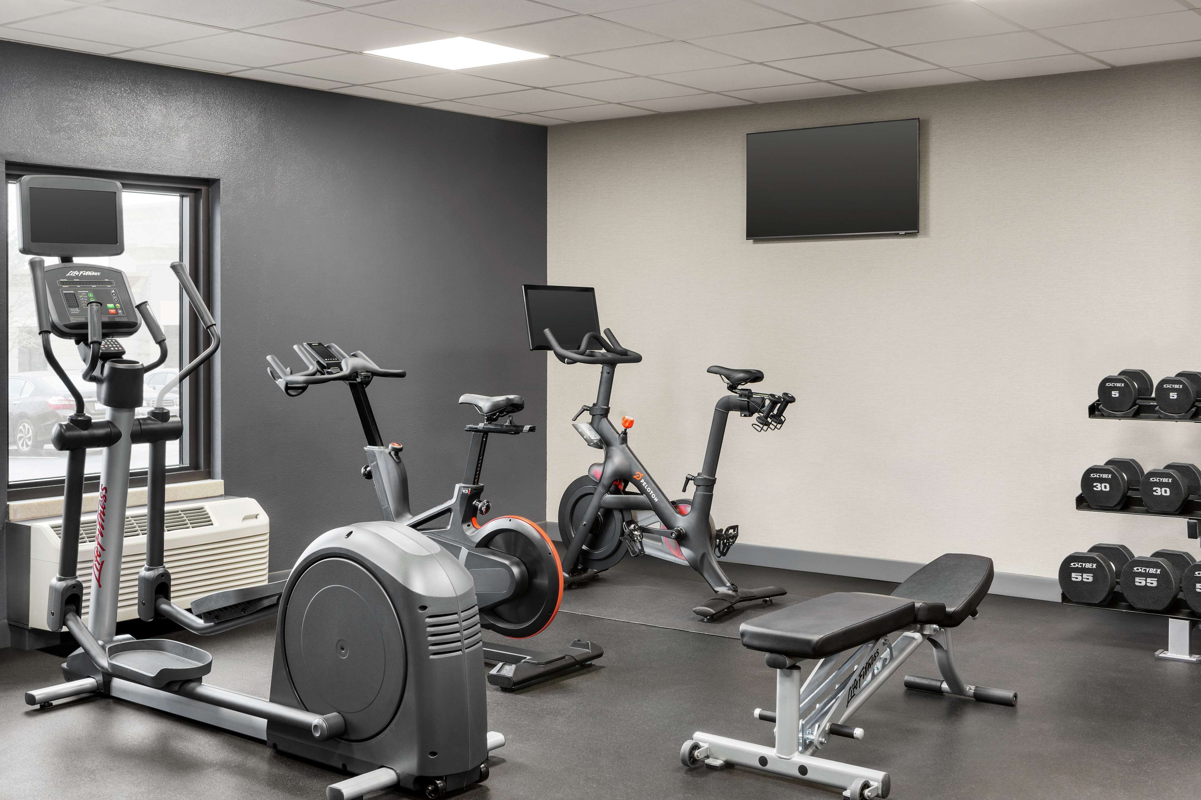 Une salle de sport équipée de divers appareils d’exercice, notamment des tapis de course, des vélos d’appartement et des haltères.