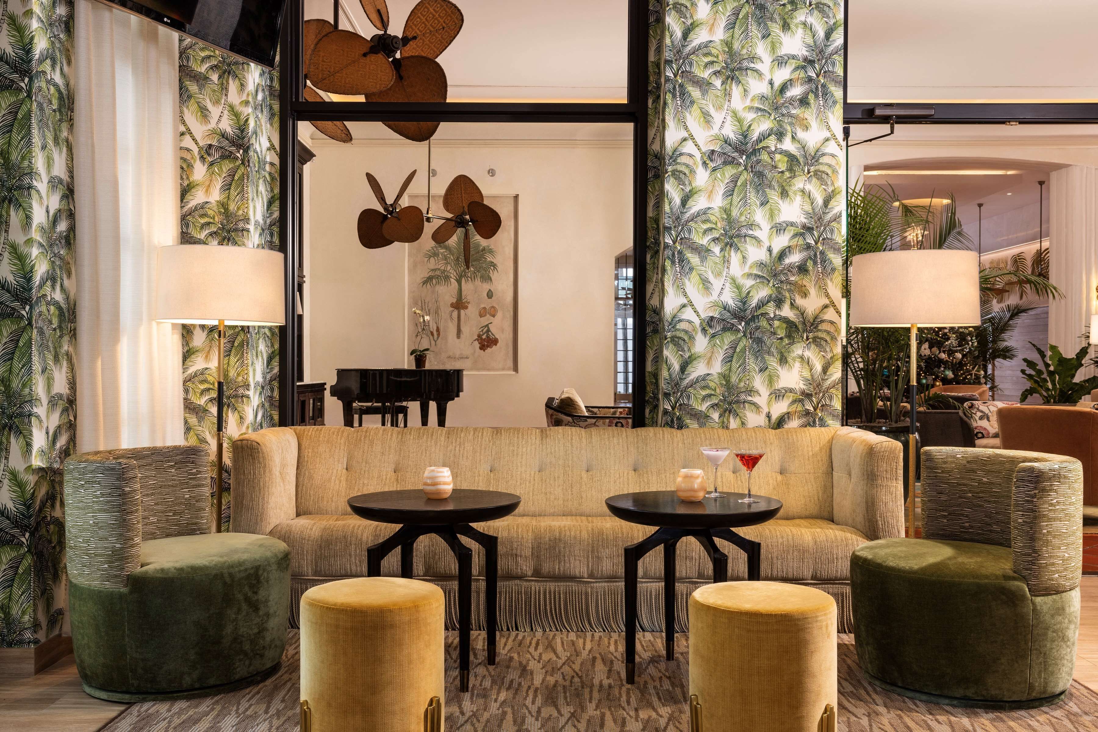 A spacious lobby with a large sofa, two armchairs, and a piano.