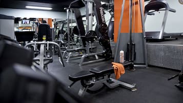 A gym with various exercise equipment, including a bench, weight machines, and a treadmill.