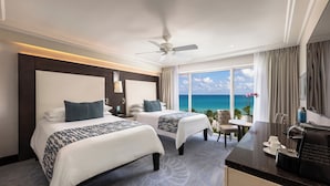 A hotel room with two beds, a ceiling fan, a view of the ocean, a dining area, and a kitchen counter. - The Palms Hotel & Spa (Miami Beach)