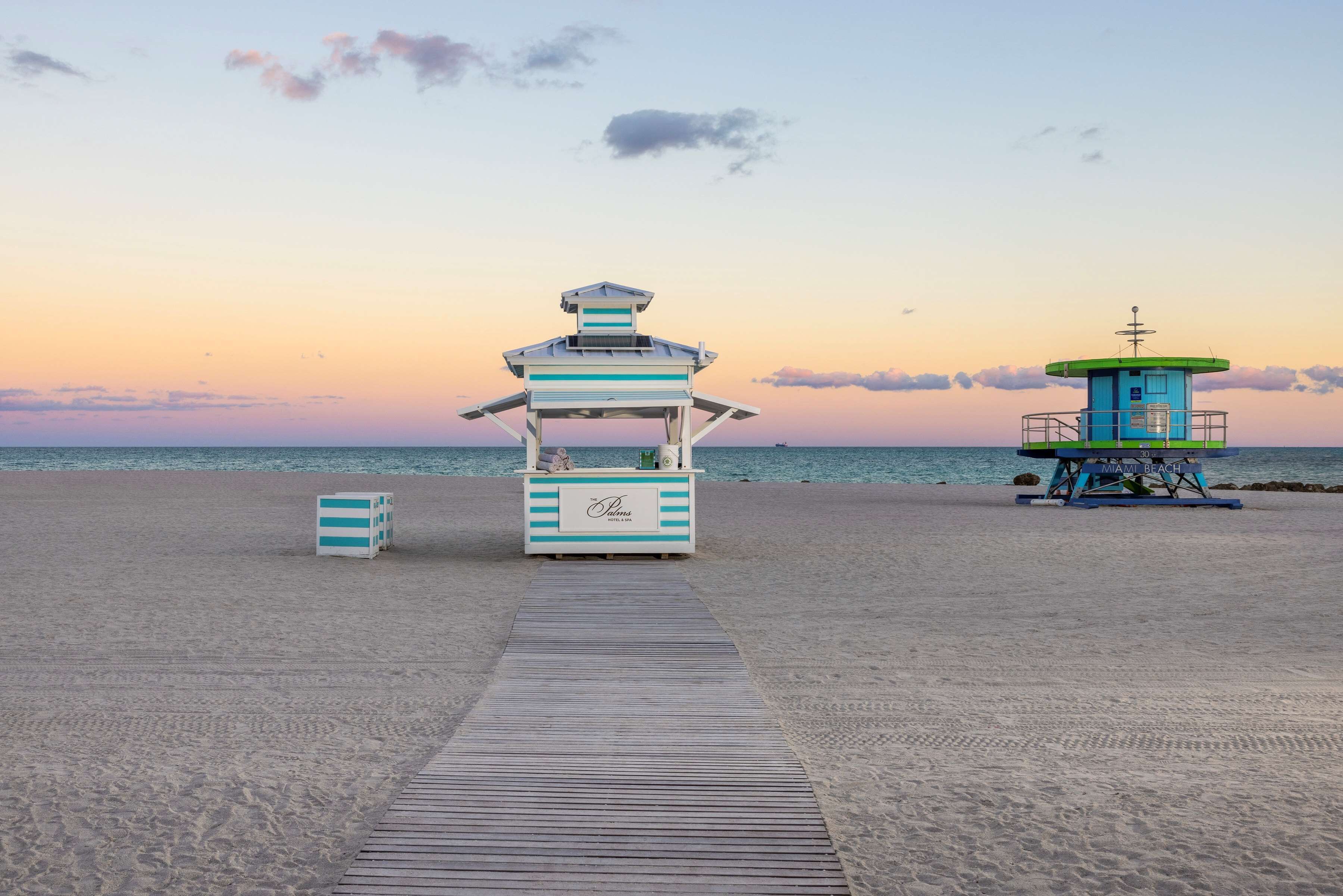A beach with a lifeguard tower and a wooden walkway leading to it.