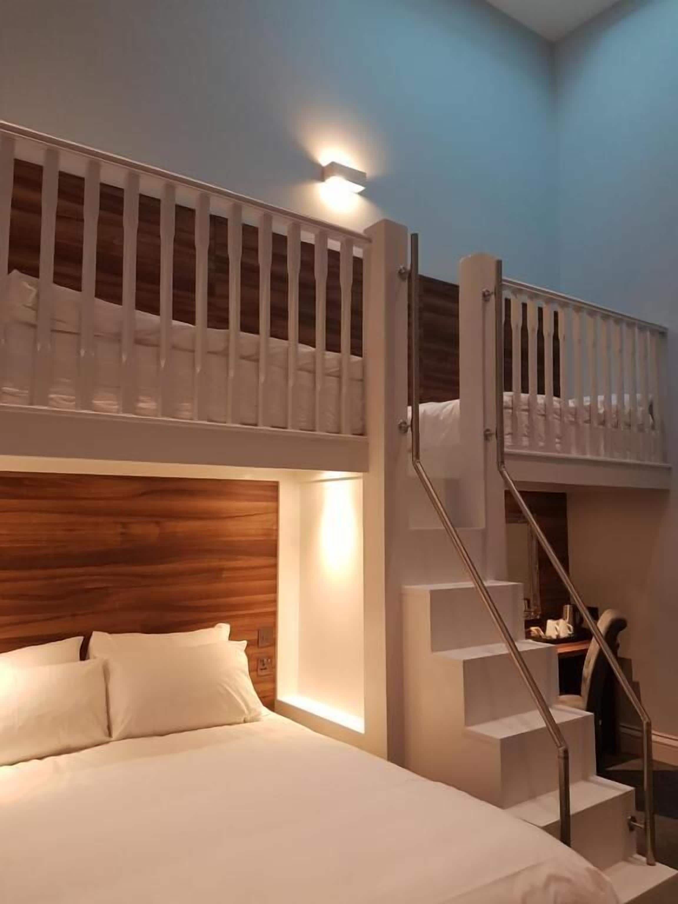 A bedroom with a bunk bed, a wooden headboard, and a staircase with a railing.