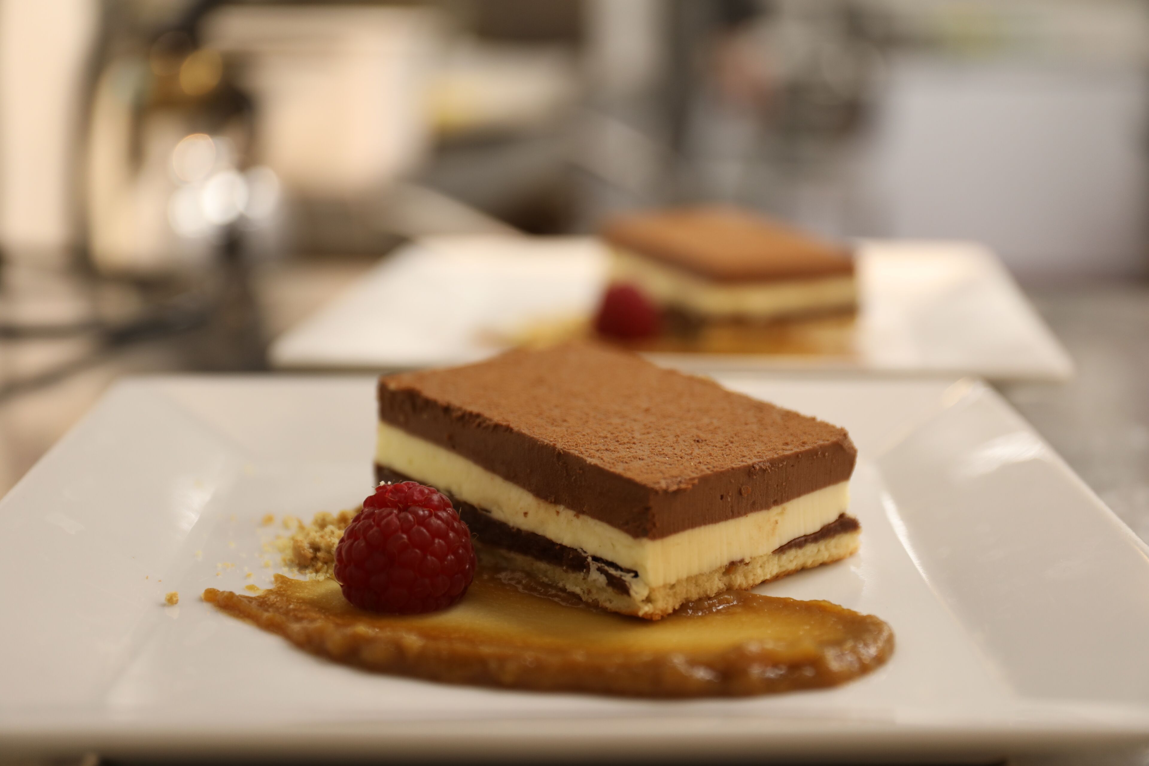 A dessert on a white plate with a raspberry and caramel sauce.
