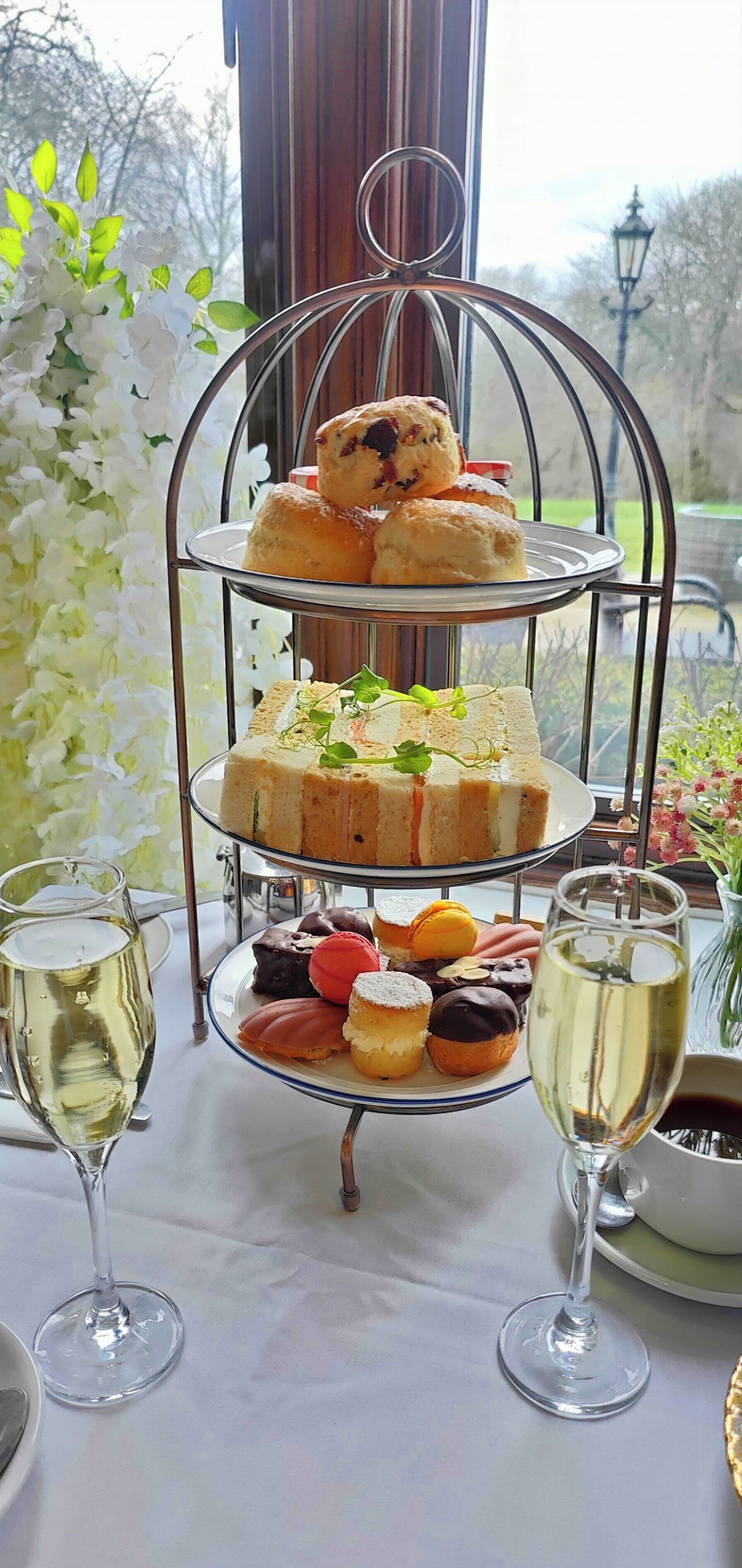 Un vassoio a tre piani con pasticcini assortiti e un bicchiere di champagne.