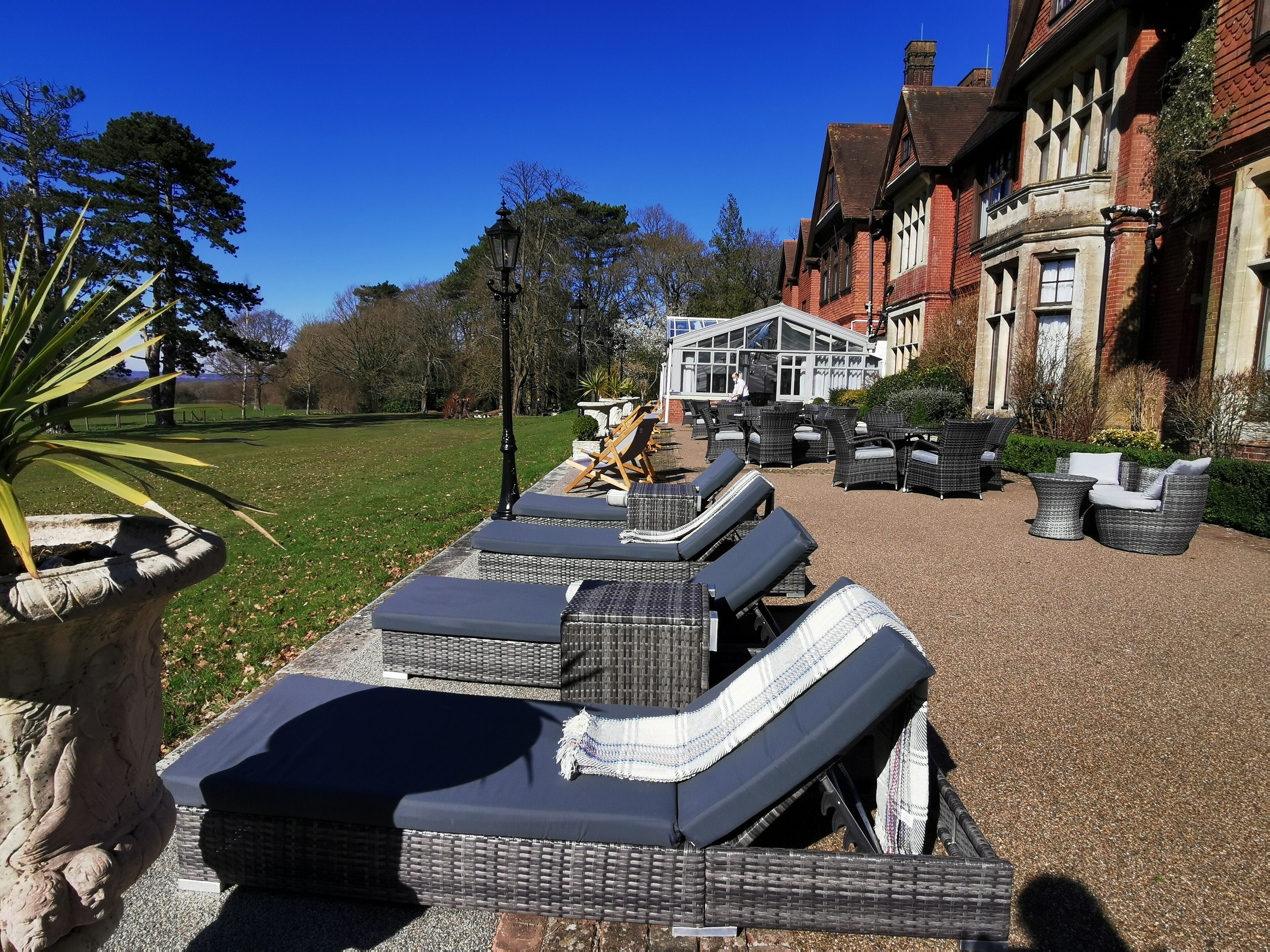 Outdoor wicker furniture arranged on a gravel area with a building in the background.