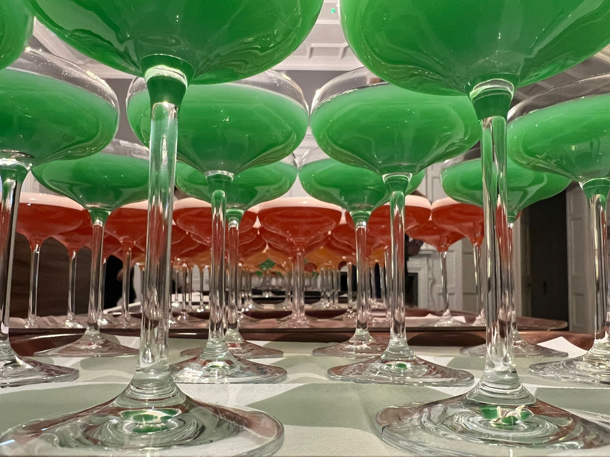 Varias copas de vidrio con líquidos rojo y verde.