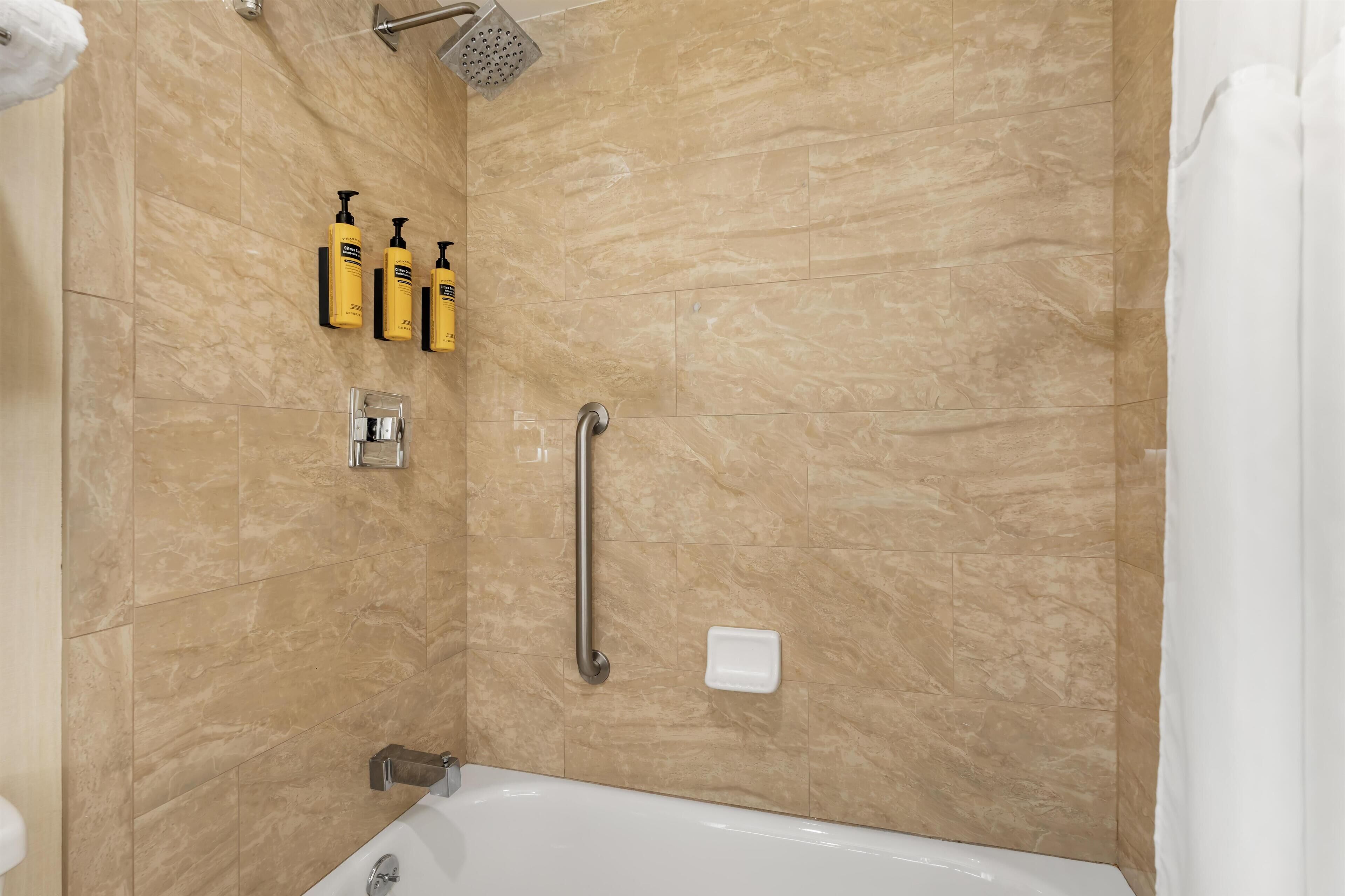 A modern bathroom with a bathtub, a shower, and a handrail.