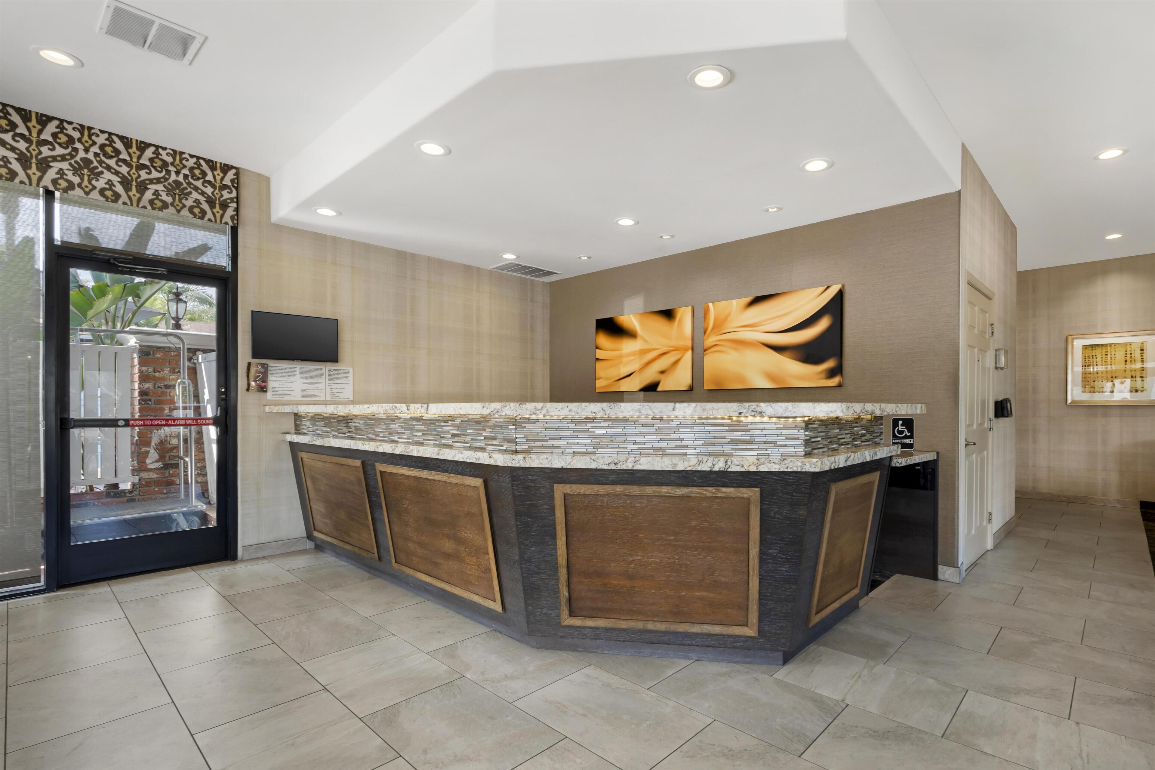 A modern kitchen with a central island, a refrigerator, and a flat-screen TV mounted on the wall.