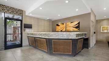 A modern kitchen with a central island, a refrigerator, and a flat-screen TV mounted on the wall.