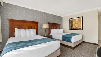 A hotel room with two beds, a large painting on the wall, and a patterned carpet.