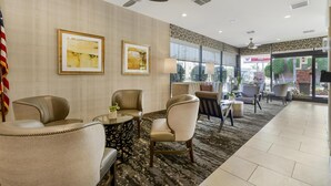 A hotel lobby with a modern design, featuring leather chairs, a glass table, and artwork on the walls.