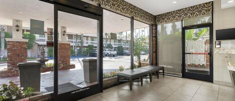 Un vestíbulo de hotel con un banco, una recepción y vistas a la calle.